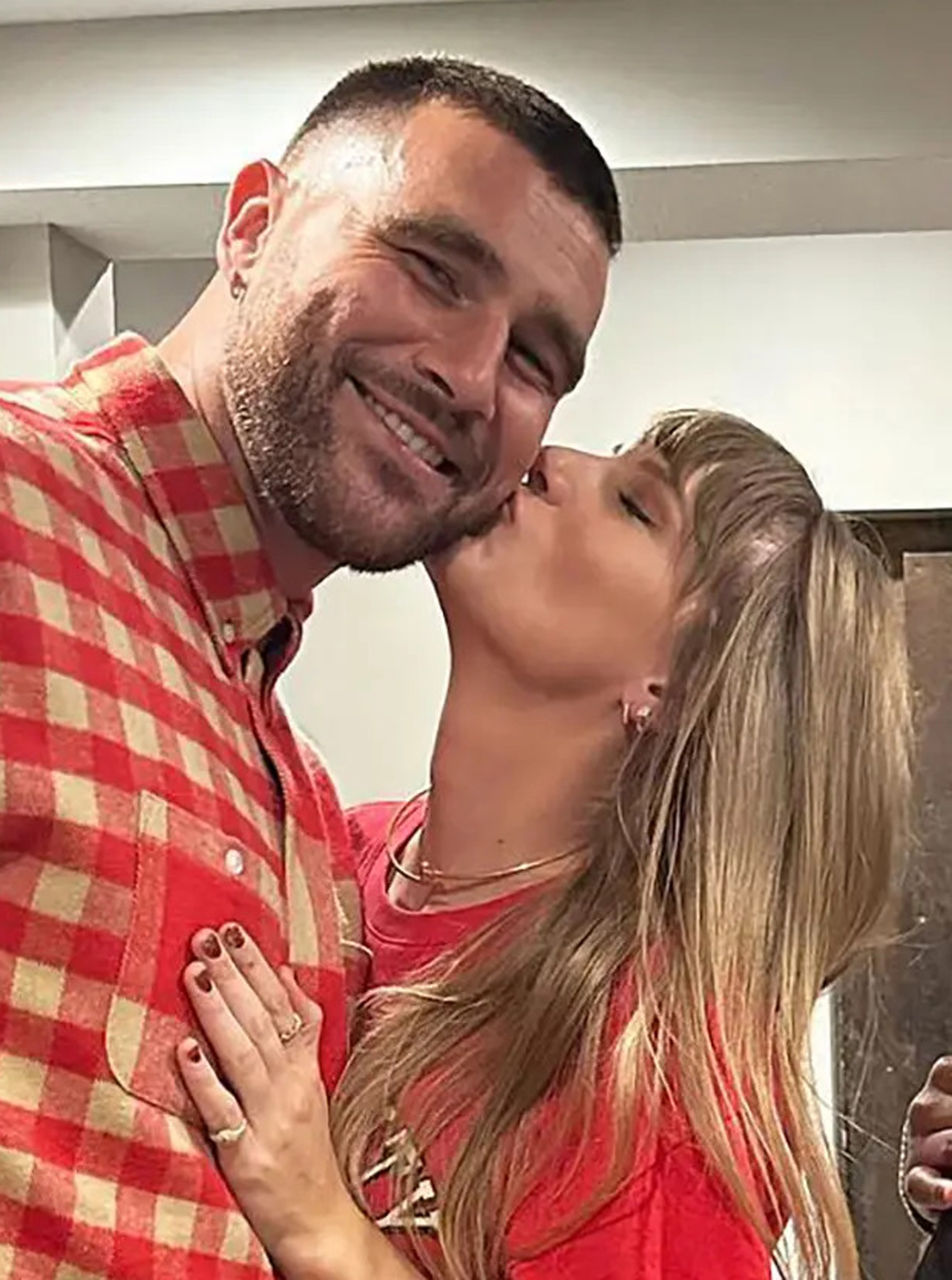 Taylor Swift kissing Travis Kelce on the cheek.