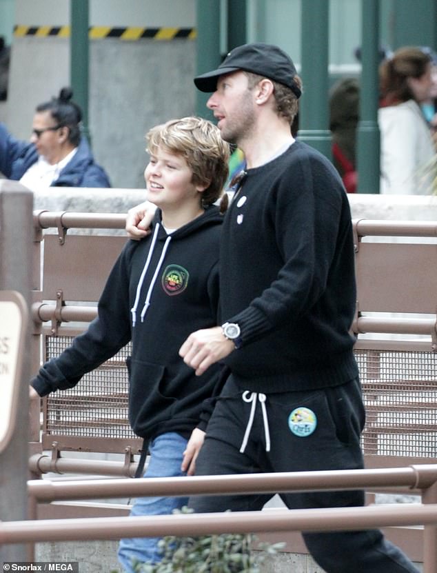 Cute: Chris wrapped an arm around youngest son Moses, 13, as the father son duo strolled through the theme park