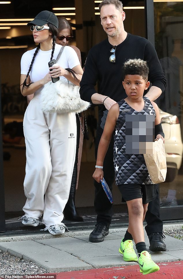 Little Saint looked adorable in a black, gray, and white basketball jersey and lime green Nike sneakers