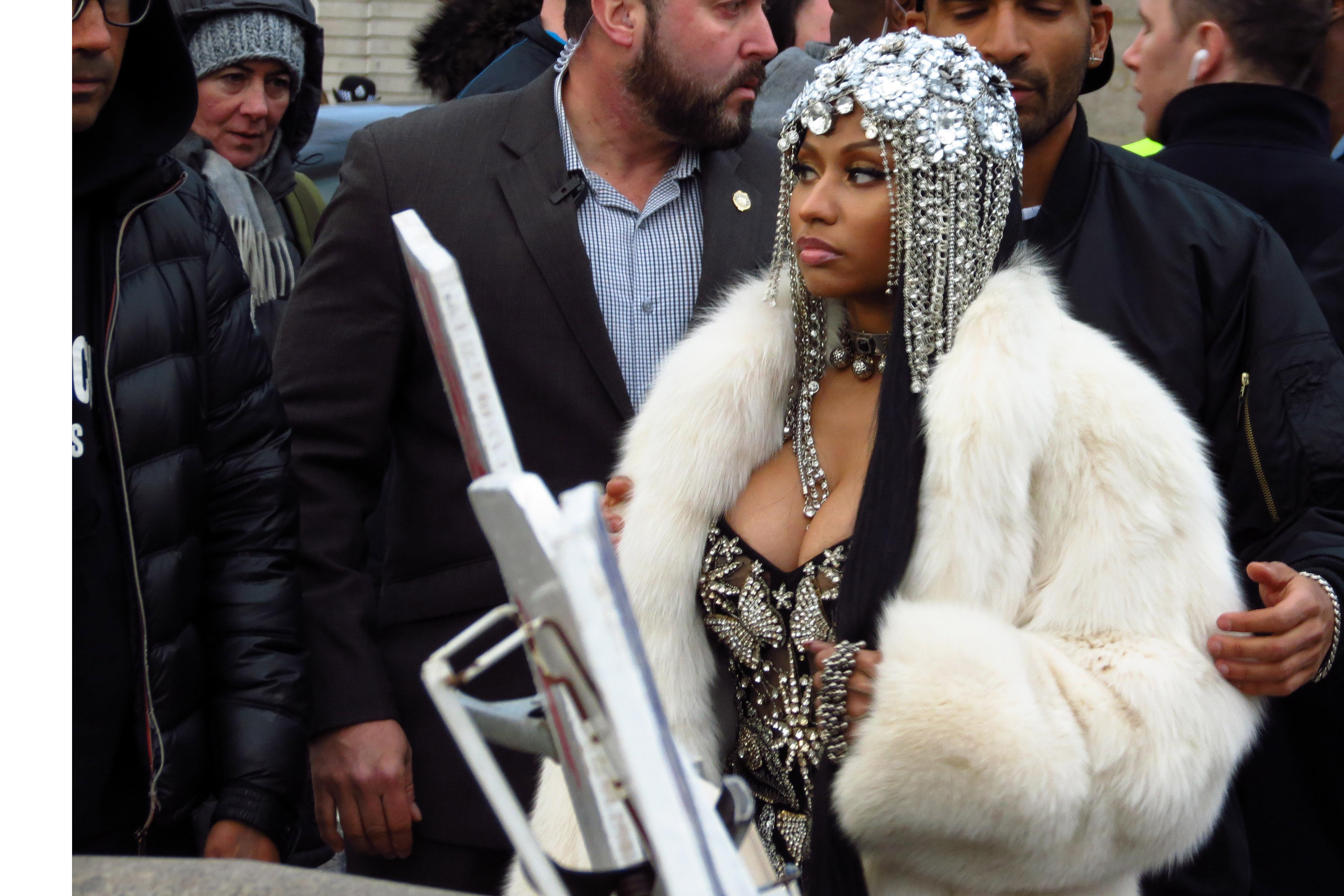  Nicki warmed up in a white fluffy coat in between takes