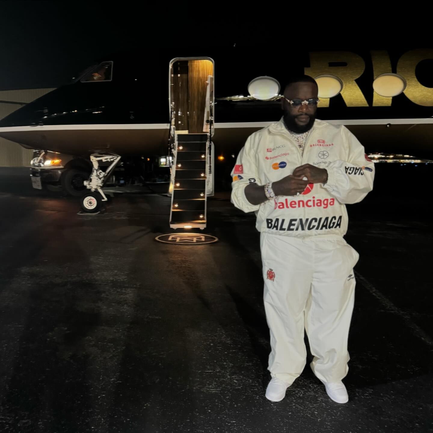 Photo shared by Rick Ross on June 15, 2024 tagging @untouchablemmg, @officialbelaire, @theslipperysoap, and @rickrosscarshow. May be an image of 1 person, standing, airplane, sweatsuit and text.