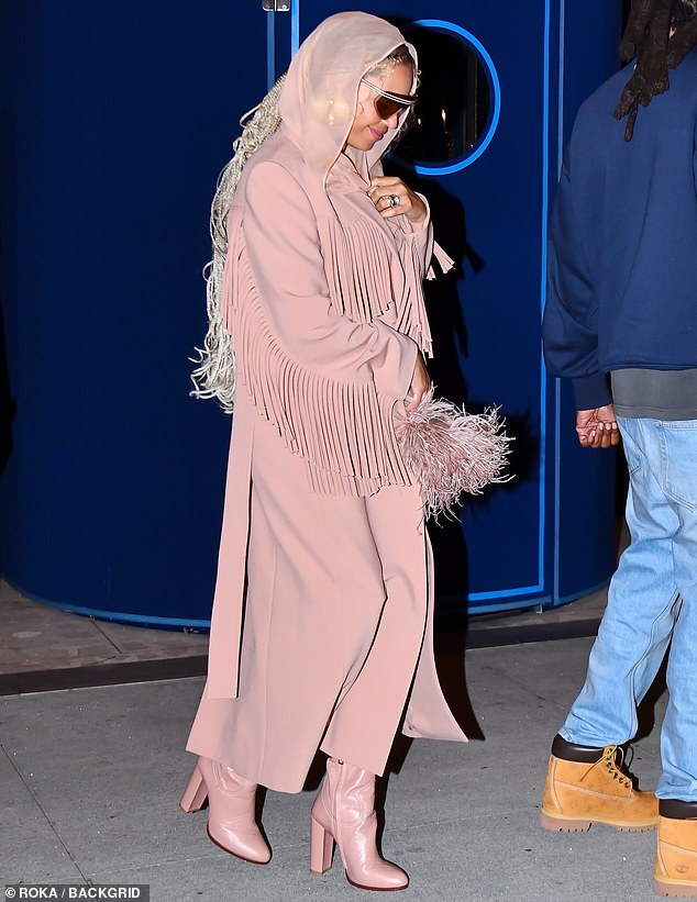 She continued to embrace her inner cowgirl in a pastel pink coat with a tasseled fringe and added a semi-sheer scarf that was wrapped around her head