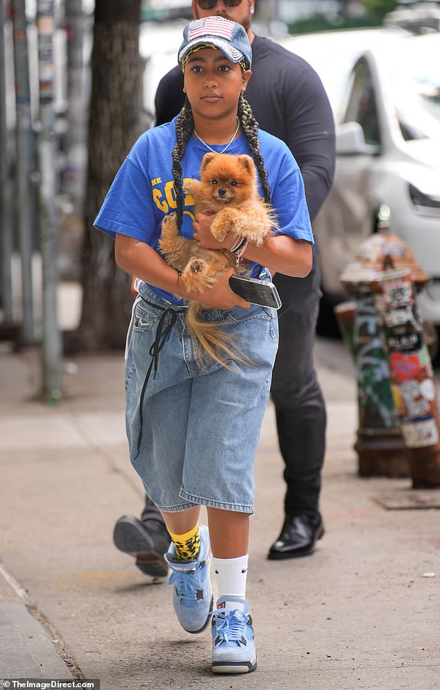 North, 11, wore long jean shorts, a blue T-shirt, and blue Jordan sneakers as she carried their small family pooch